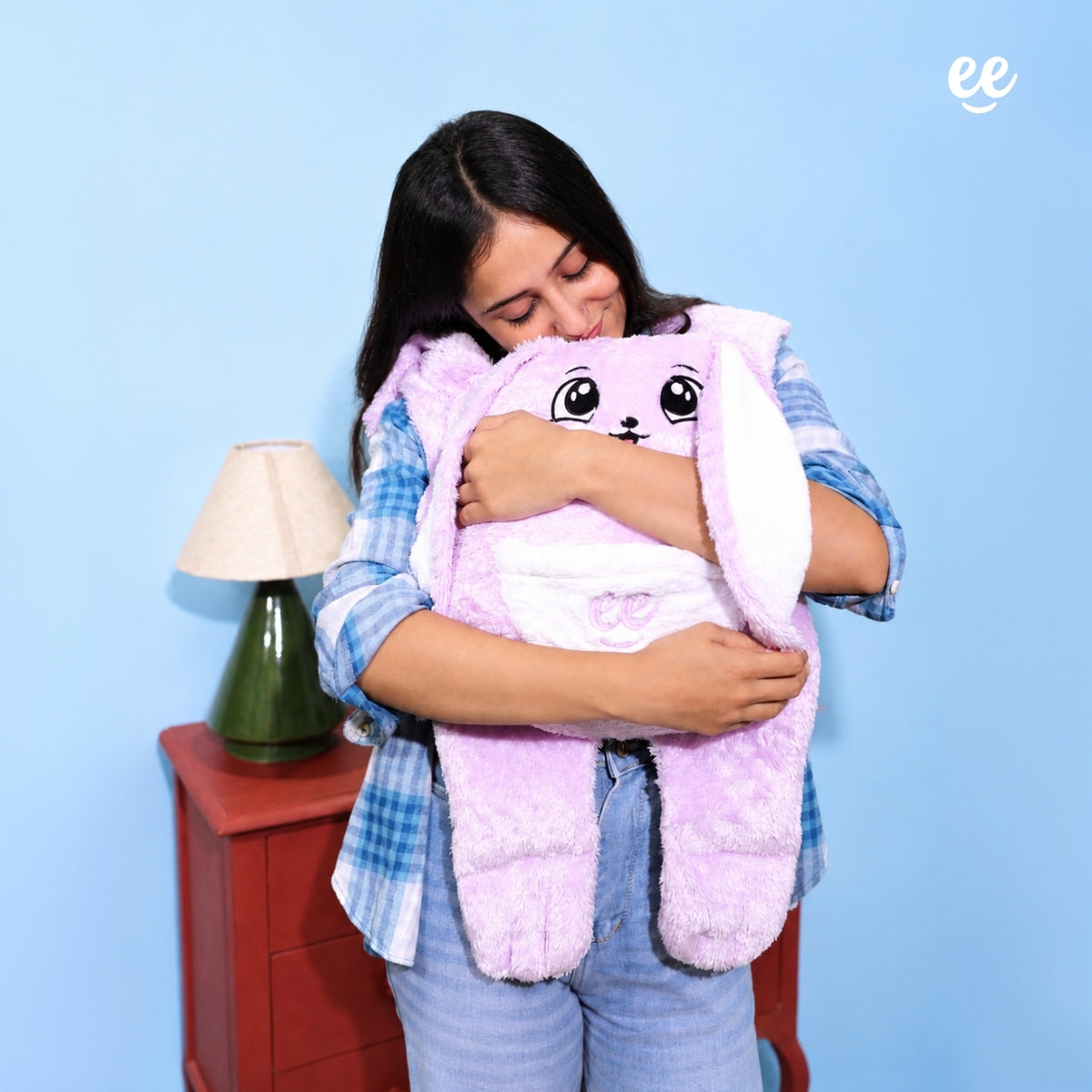 Woman hugging Warmlee purple weighted plushie against a blue background